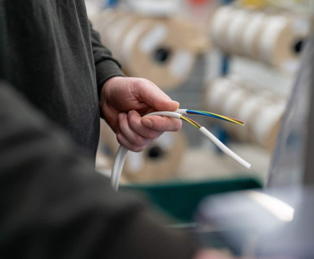 Technician holding stripped electrical cable wires during assembly process
